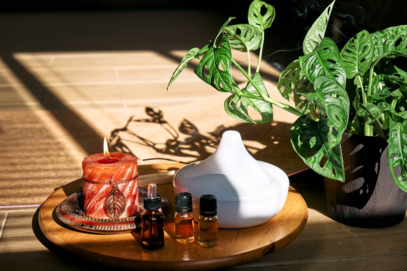Essential oil diffuser, burning candle, different types of oils and essences near yoga mat. Aromatherapy, wellness, meditation and alternative medicine concept. Natural remedies.