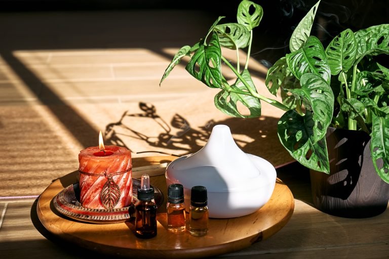 Essential oil diffuser, burning candle, different types of oils and essences near yoga mat. Aromatherapy, wellness, meditation and alternative medicine concept. Natural remedies.